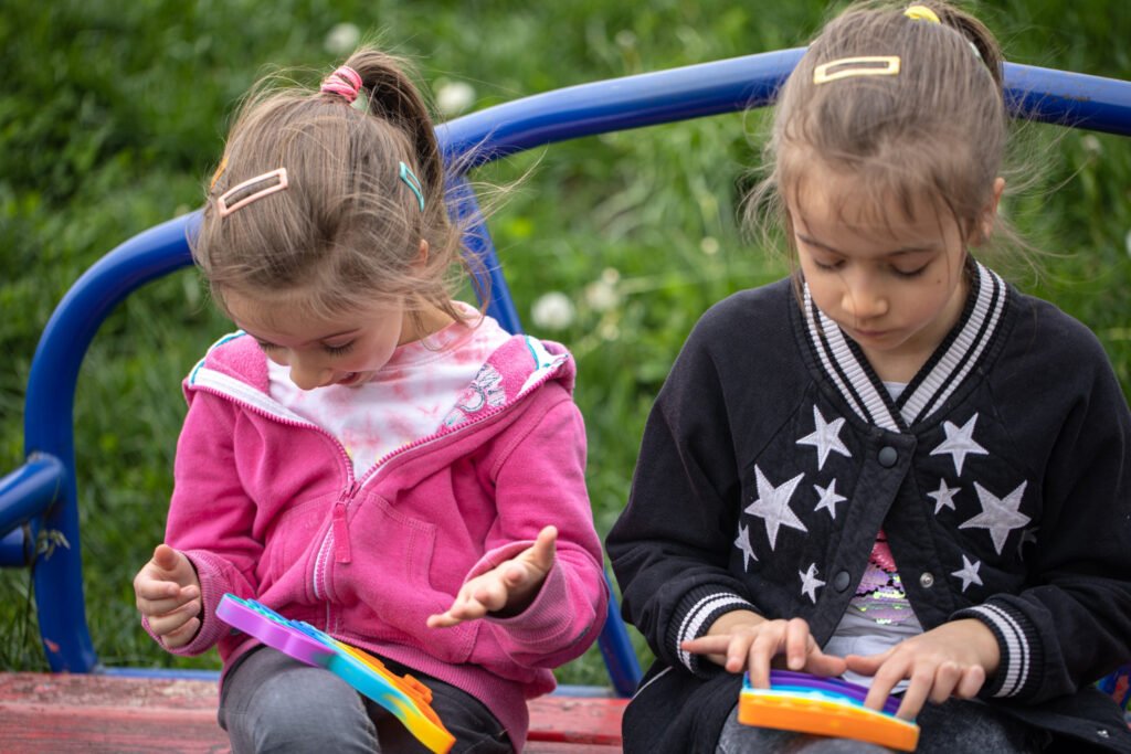 Two young girls playing with colorful toys at a playground