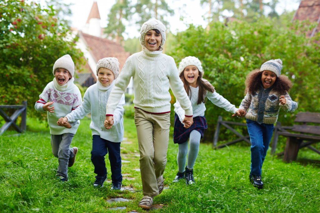 Children and a parent running joyfully across a grassy park