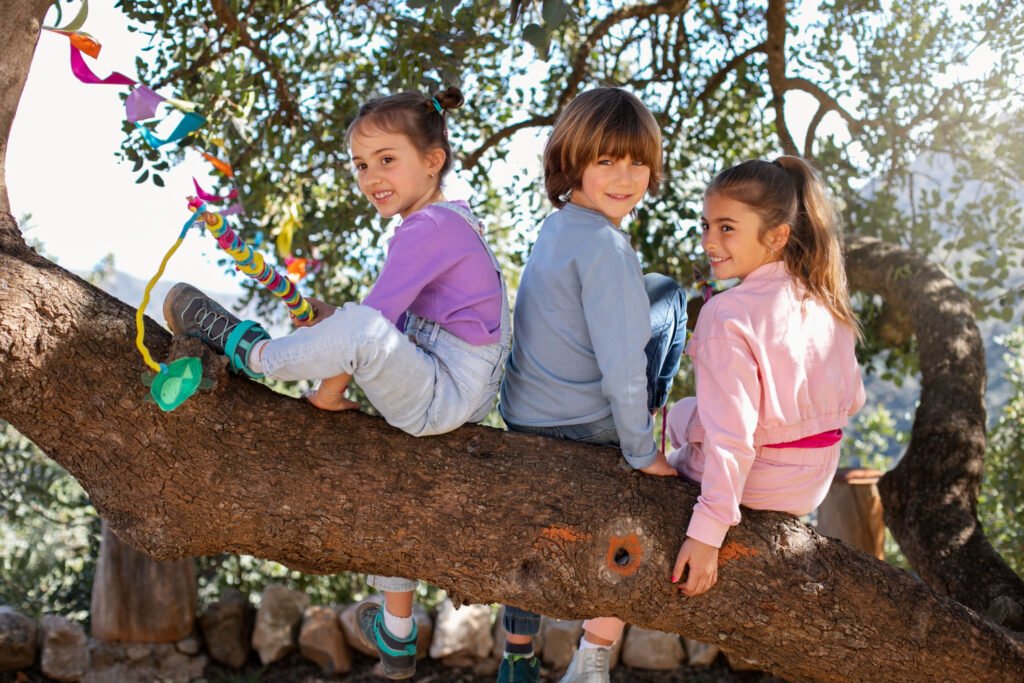 Children sitting together on a large tree branch